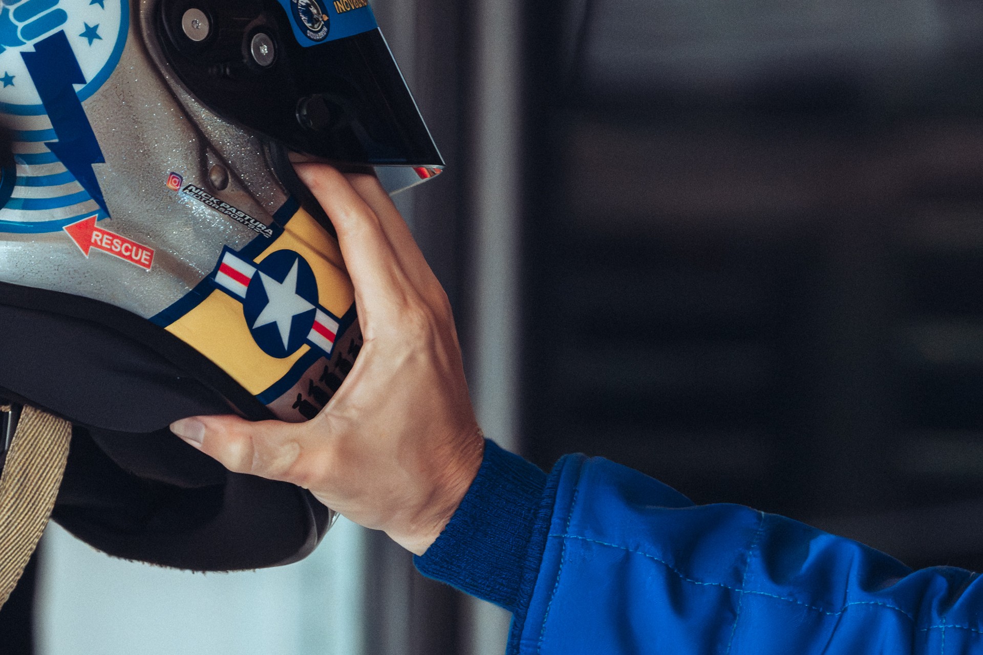 Close-up of a hand gripping a racing helmet with military star decal